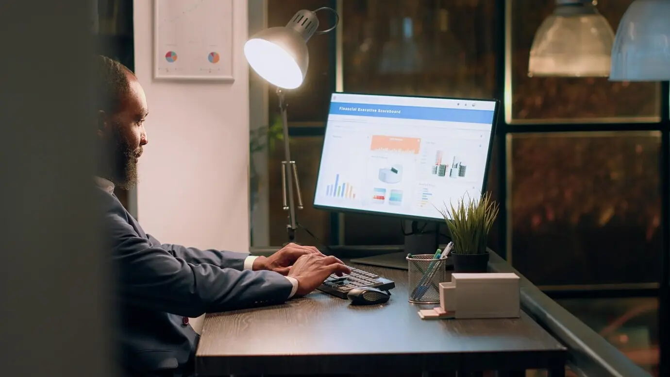 Müder Buchhalter, der Datensätze online am Computer eingibt und versucht, vor der Deadline mit den Projektaufgaben Schritt zu halten. Gestresster Mitarbeiter, der über Nacht im Büro in der Nachtschicht arbeitet.